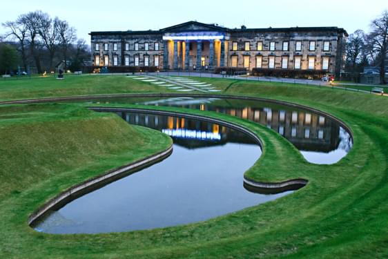 A large museum building overlooking a sculpted garden with sculpted ponds.