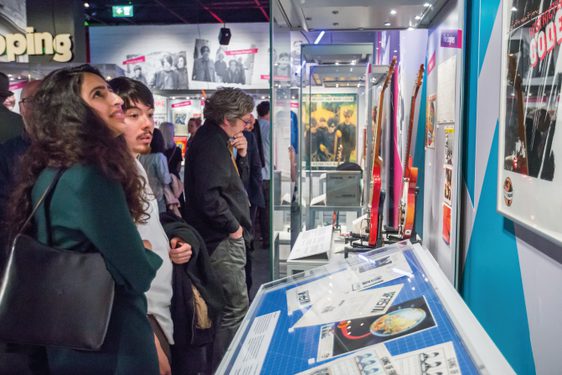 Visitors look at items in a case in a crowded gallery