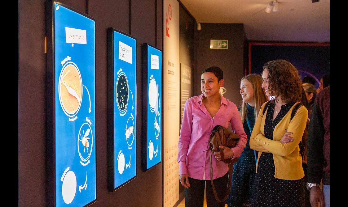 Visitors looking at screens showing cartoon illustrations of bacteria.