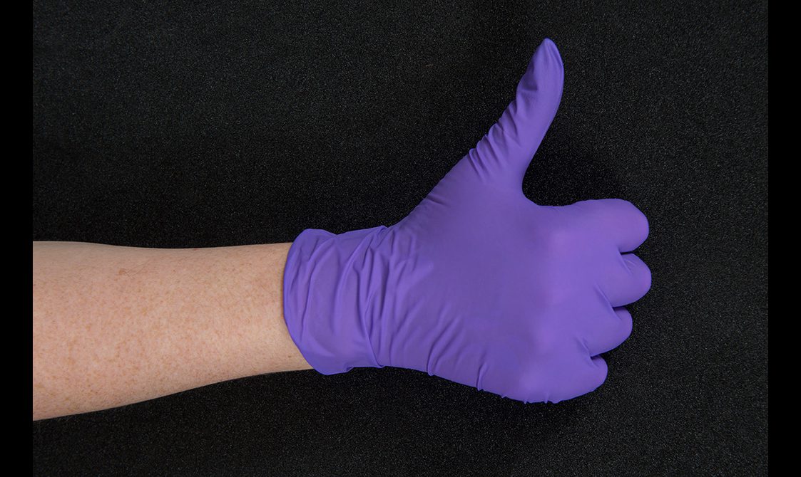 Close up of a hand wearing a purple nitrile glove giving a thumbs up.