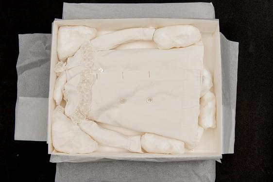 A small white blouse packed in a cardboard box with tissue puffs.
