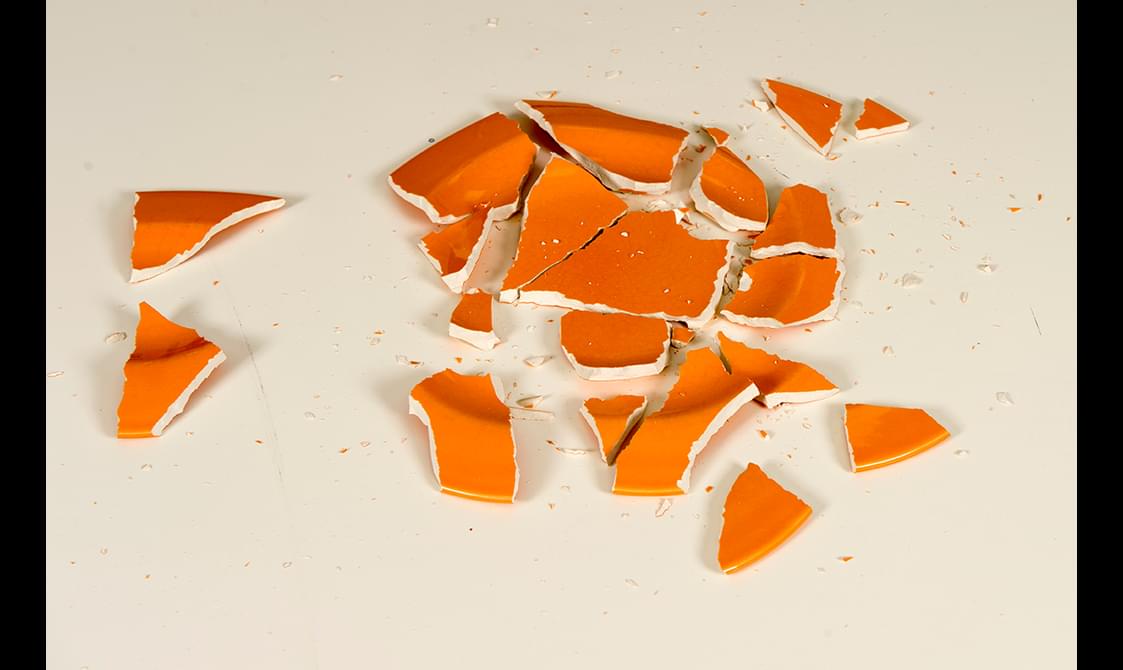 Shards of a broken orange ceramic plate.