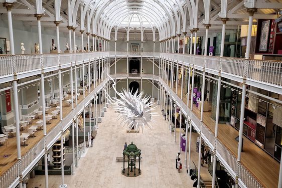 A large inflatable model of a parasite hanging from the ceiling of a multi-storey museum gallery.
