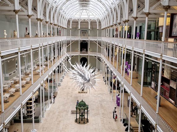 A large inflatable model of a parasite hanging from the ceiling of a multi-storey museum gallery.