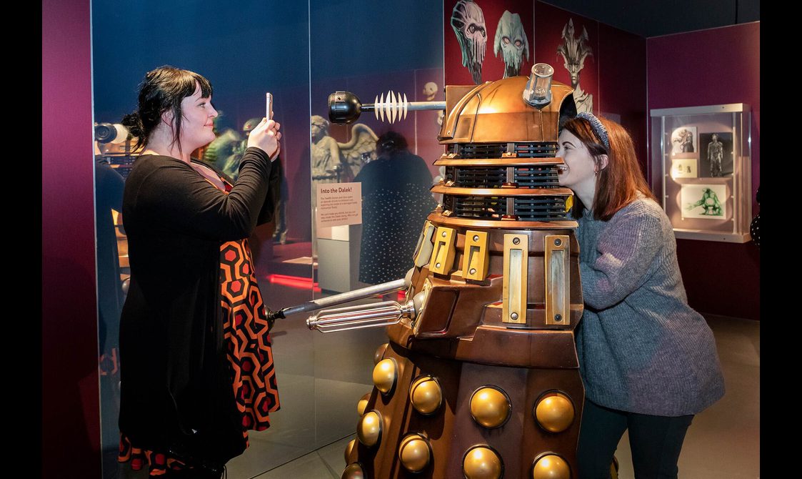 A visitor posing inside a dalek costume while getting her photograph taken by a friend.