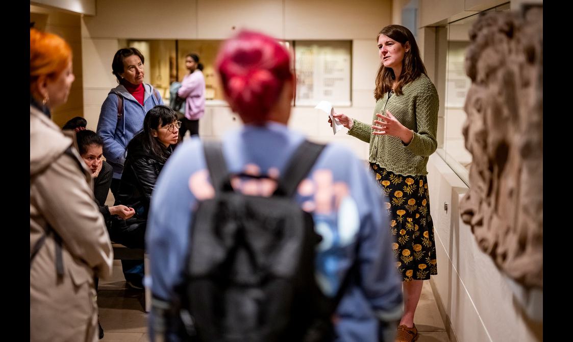 A curator talks to a group of visitors in a museum gallery space.