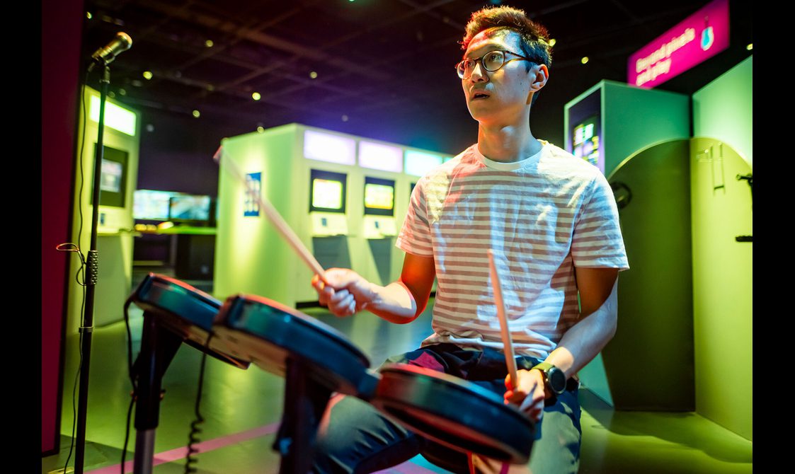 A gamer plays the drum kit in Guitar Hero.