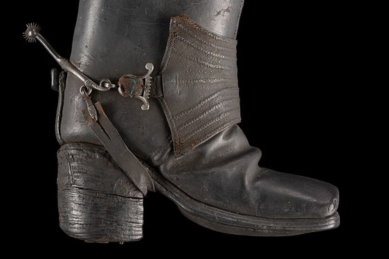 Side angle of a 17th century Jack boot propped up against a black background.