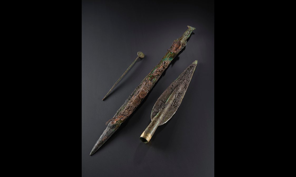 A Bronze Age disc-headed pin, sword and spearhead. The remnants of a wooden scabbard are laid on the sword.
