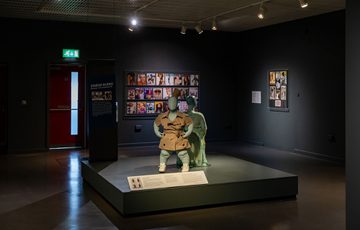 Two mannequins styled with garments on a platform within the exhibition.
