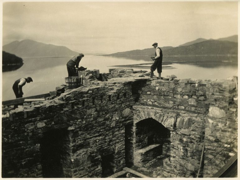 a sepia photgraph showing men in flat caps working to lay bricks on the walls at Eilean Donan.