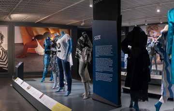 Ten mannequins arranged across the exhibition with photographic backdrops.
