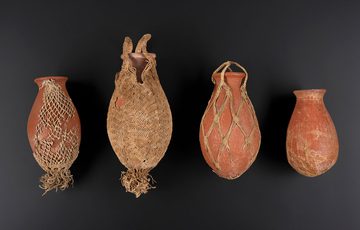 Four terracotta oval shaped vases. Each pot is wrapped in net bags knotted in different ways.