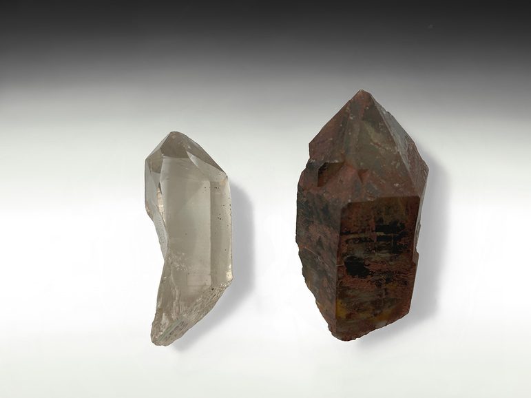 A transparent colourless crystal of quartz, next to one that is brown and opaque