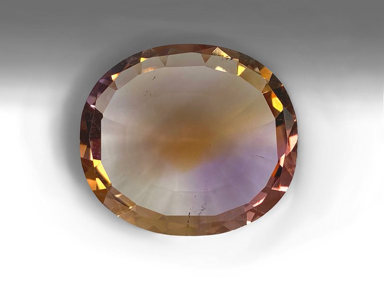 A half purple-half orange clear faceted quartz gemstone