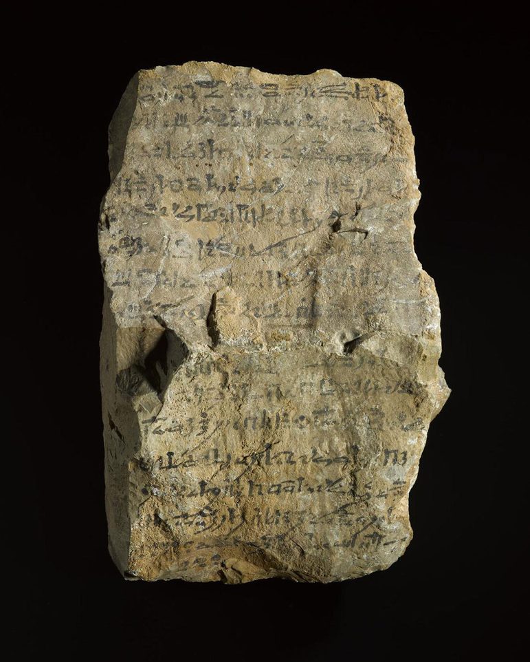 A large yellowed stone inscribed with text written in black ink
