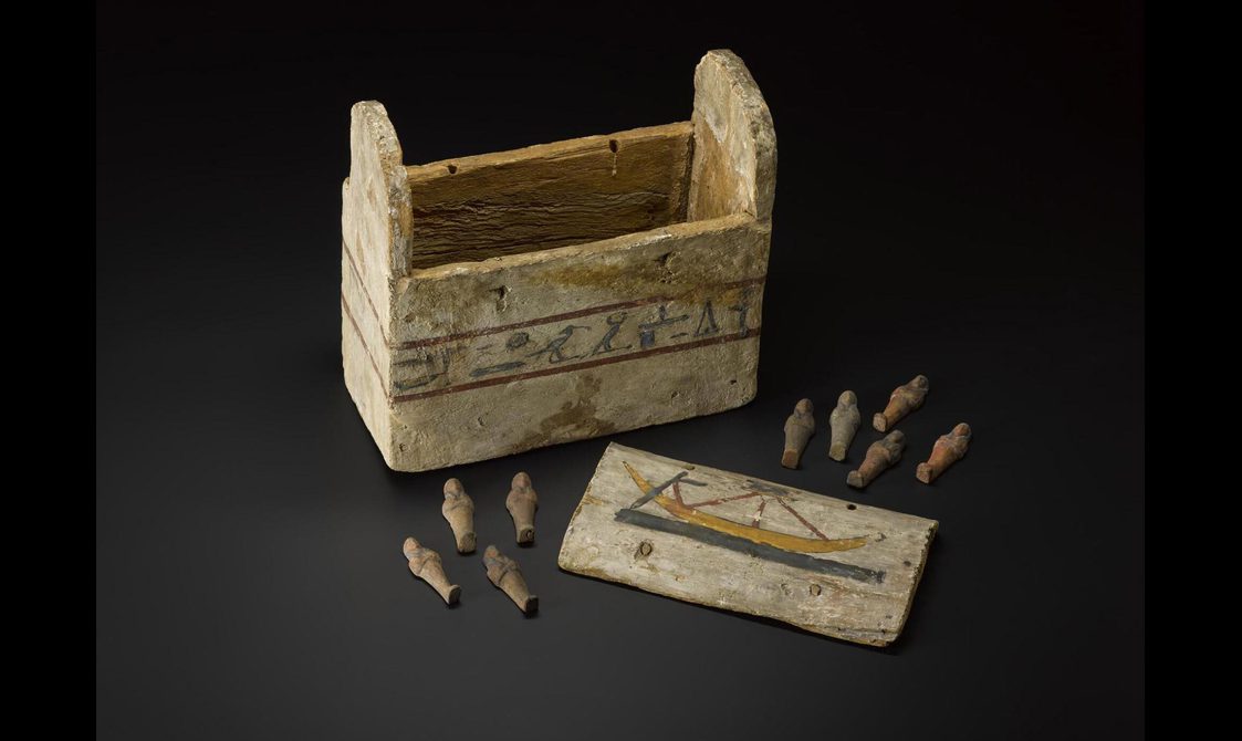 A wooden box painted white with its lid opened and contents on display.