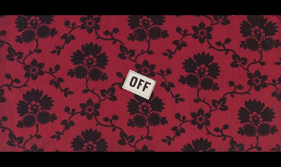 Black flowers set against red background fabric, a small label with a word "off" placed in the center of the fabric