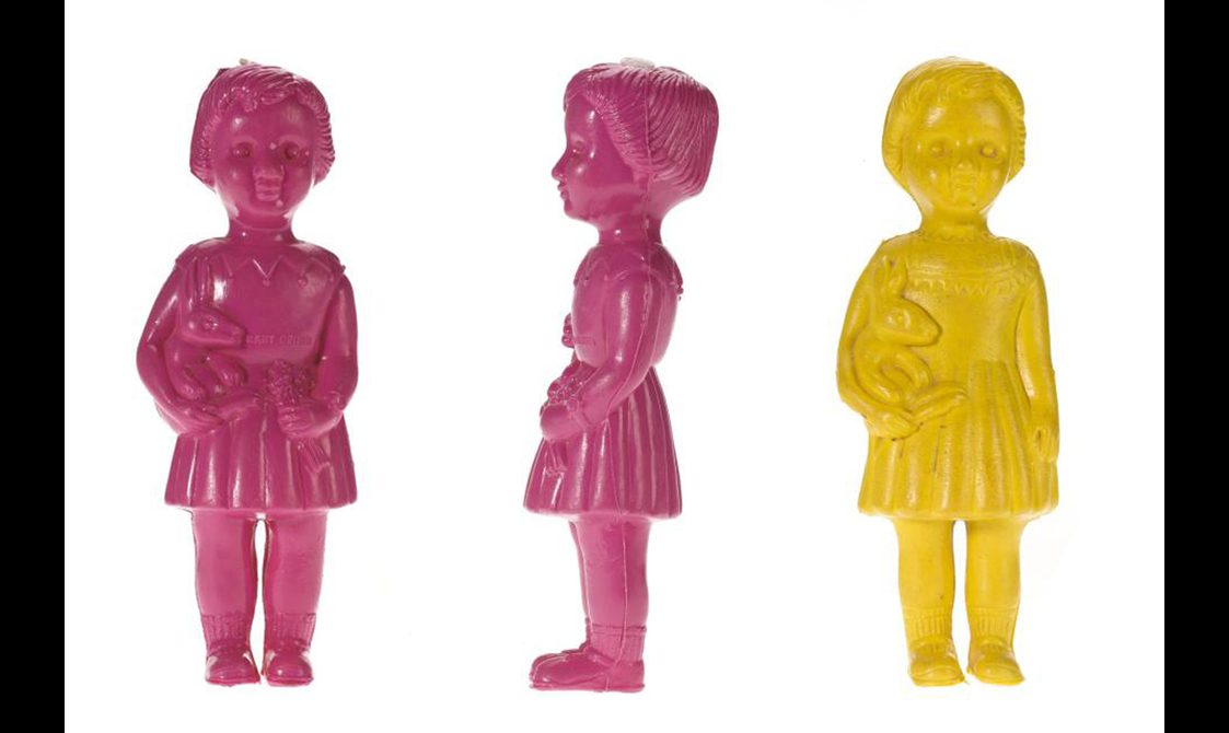 Two pink and one yellow doll in the shape of a little girl holding a rabbit toy.