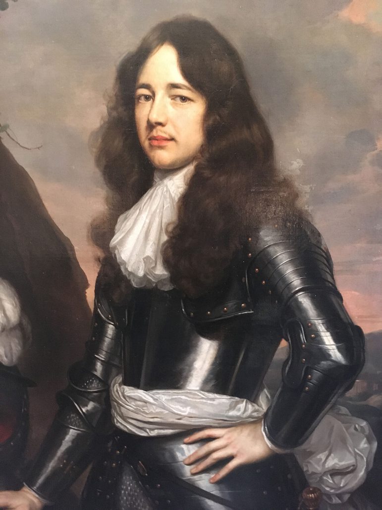 A painting of a man shown from the waist up. He has long brown wavy hair and is wearing a suit of armour with a white ruffled necktie and a white sash around his waist.