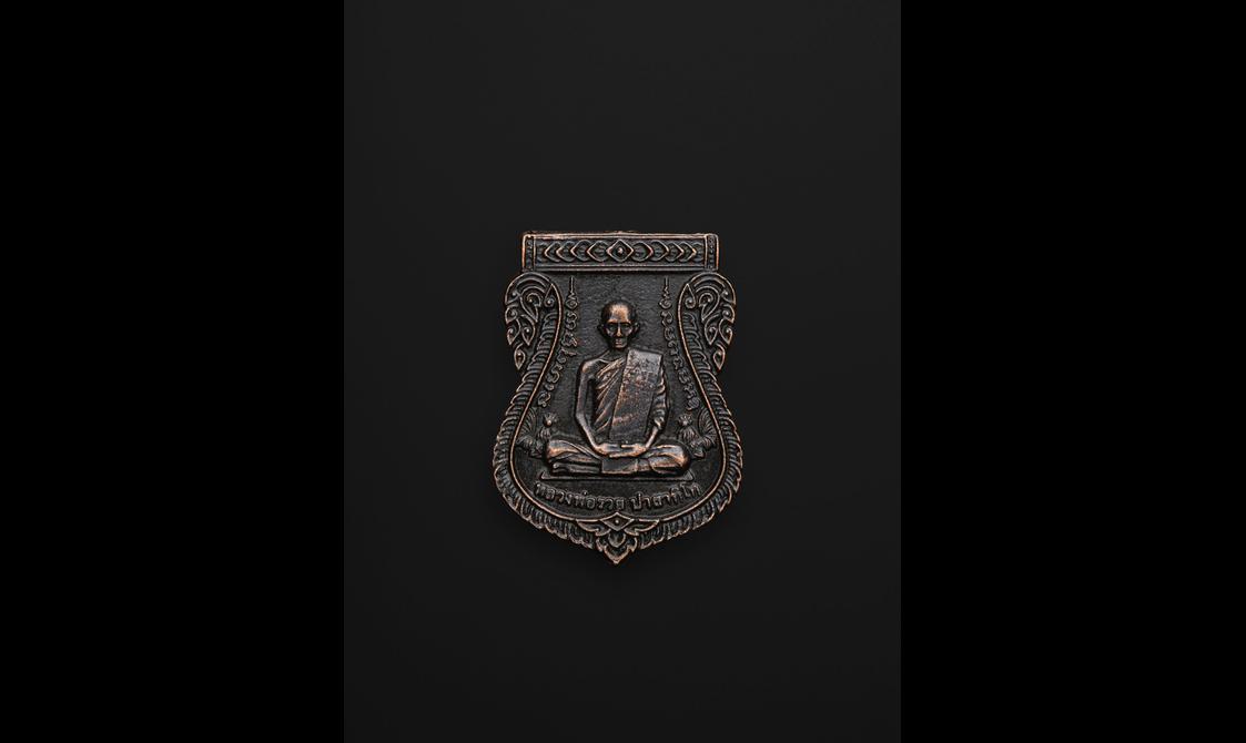 A small amulet in the shape of a shield with a Buddha figure carved on it.