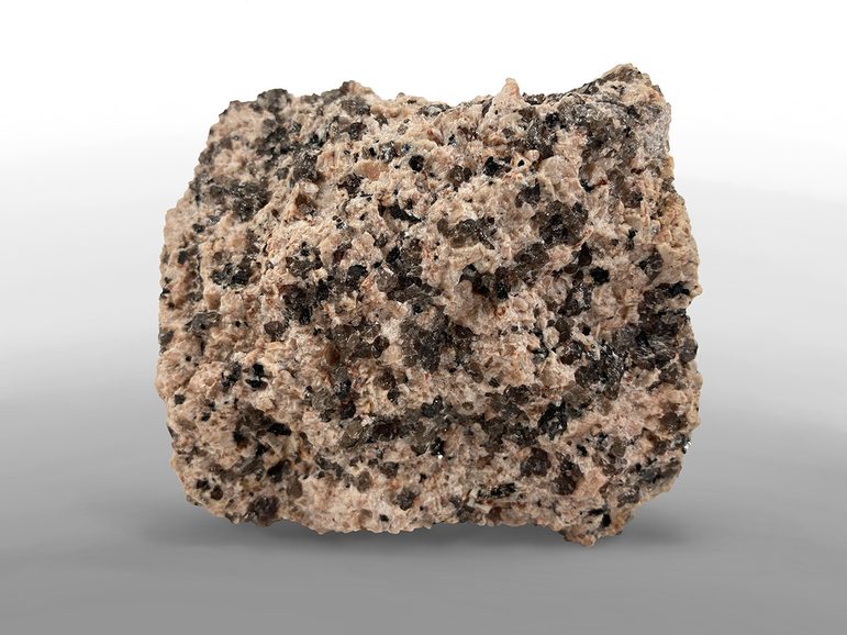 A lump of mainly pink granite, with speckles of glassy brown inclusions