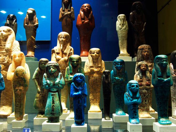 A variety of small Ancient Egyptian statues of humans with arms crossed.