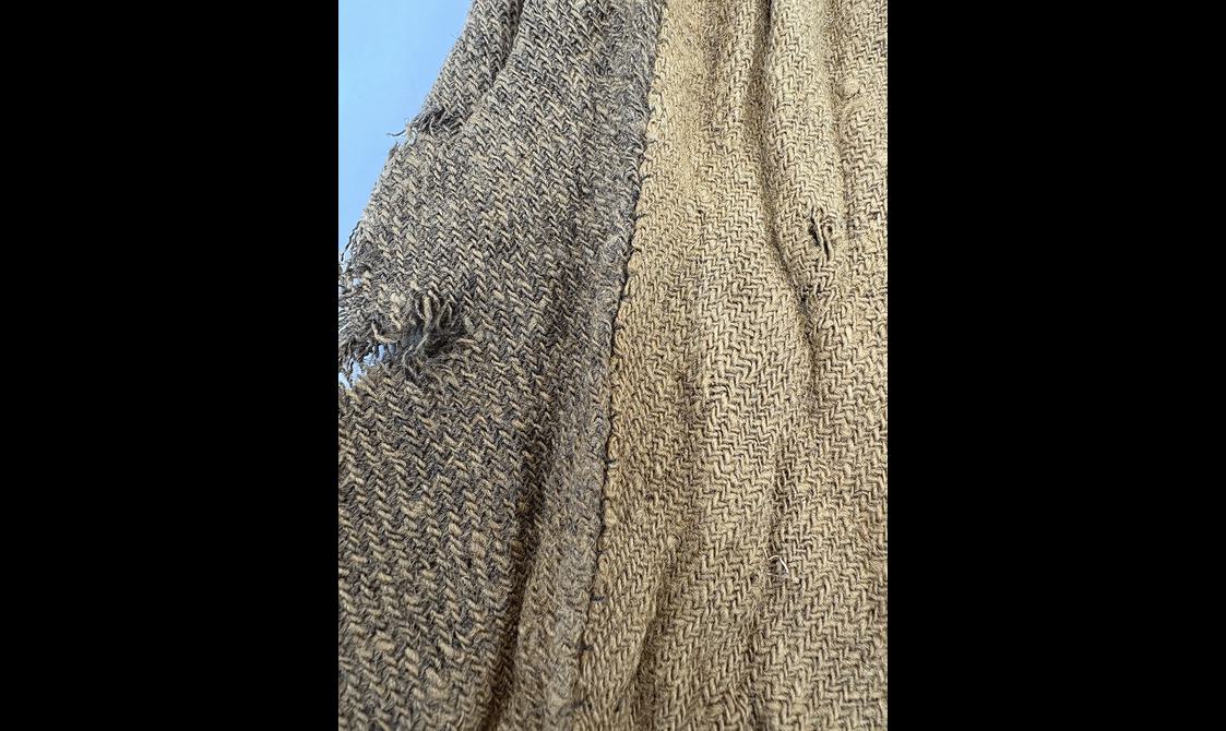 Fabric on 18th century menswear jacket inside showing repair stitching on the side vents.