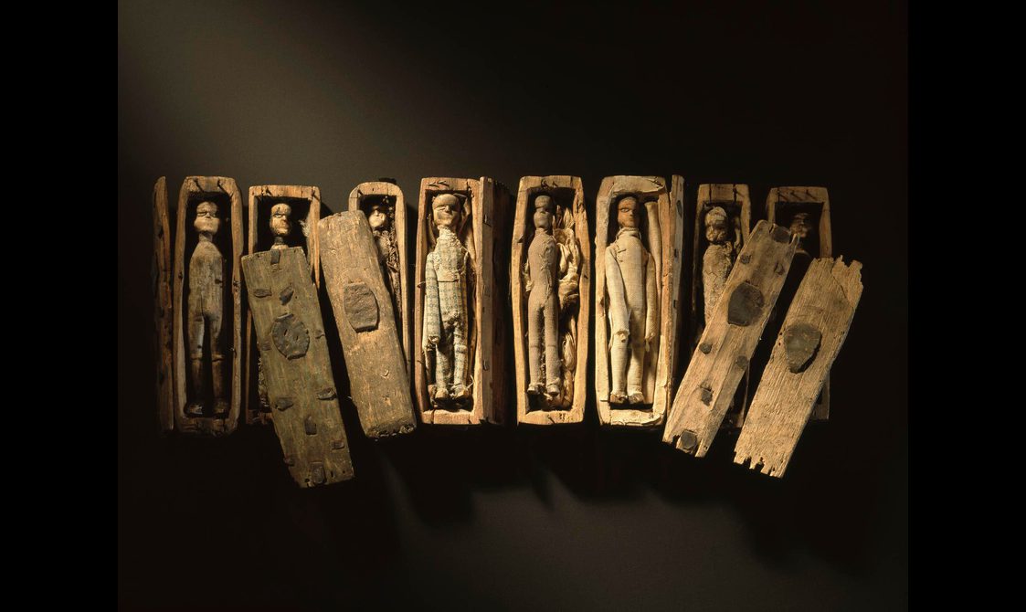Set of miniature wooden coffins with wooden dolls inside.
