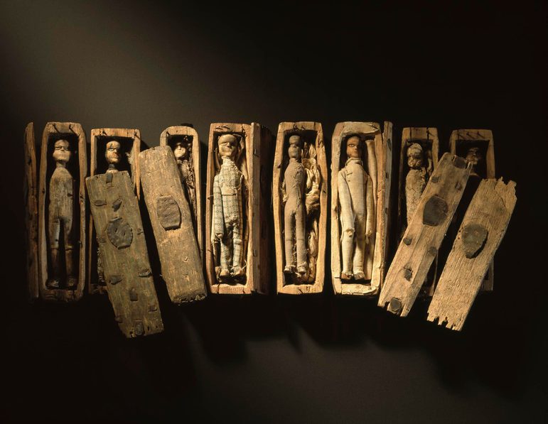 Set of miniature wooden coffins with wooden dolls inside.
