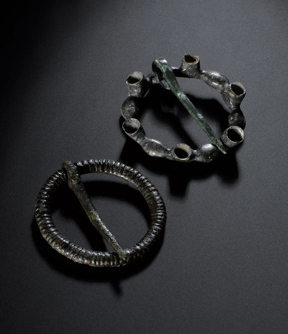 Two circular metal brooches with pins across the centres.