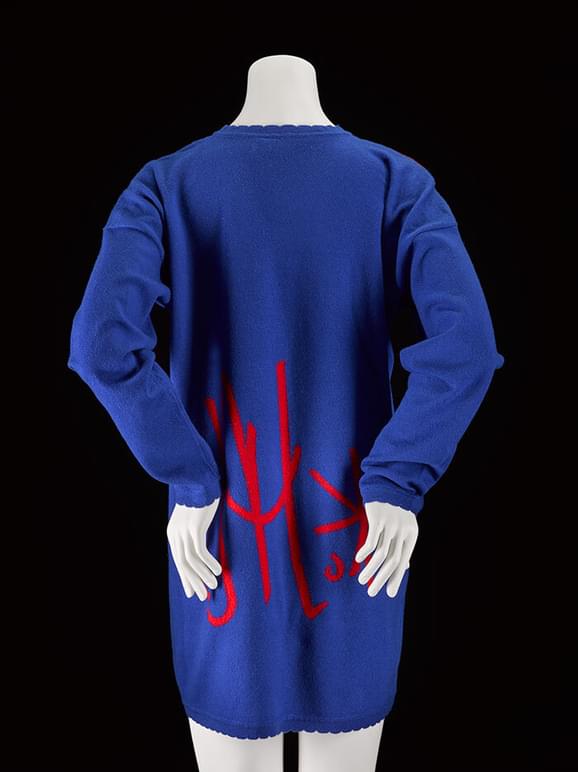 Back view of a mannequin wearing a long blue jumper with red detail