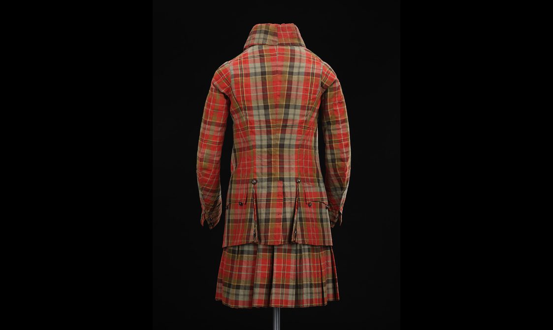 A mannequin from the back wearing a red tartan kilt and matching jacket.