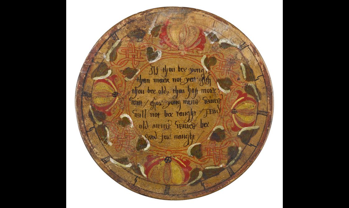 A round wooden object with text in the middles and a decorative boarder