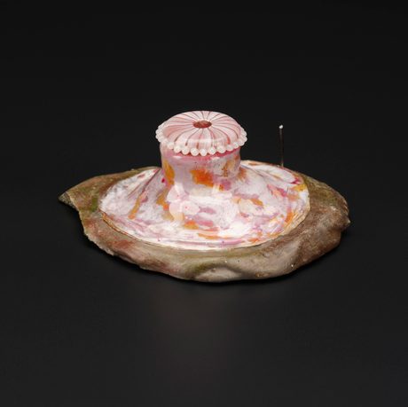 A colourful glass sculpture of a brown disk with a pink and orange jellyfish like creature on top