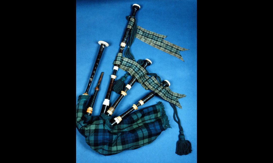 Spread out blue tartan bagpipe displayed against light blue background