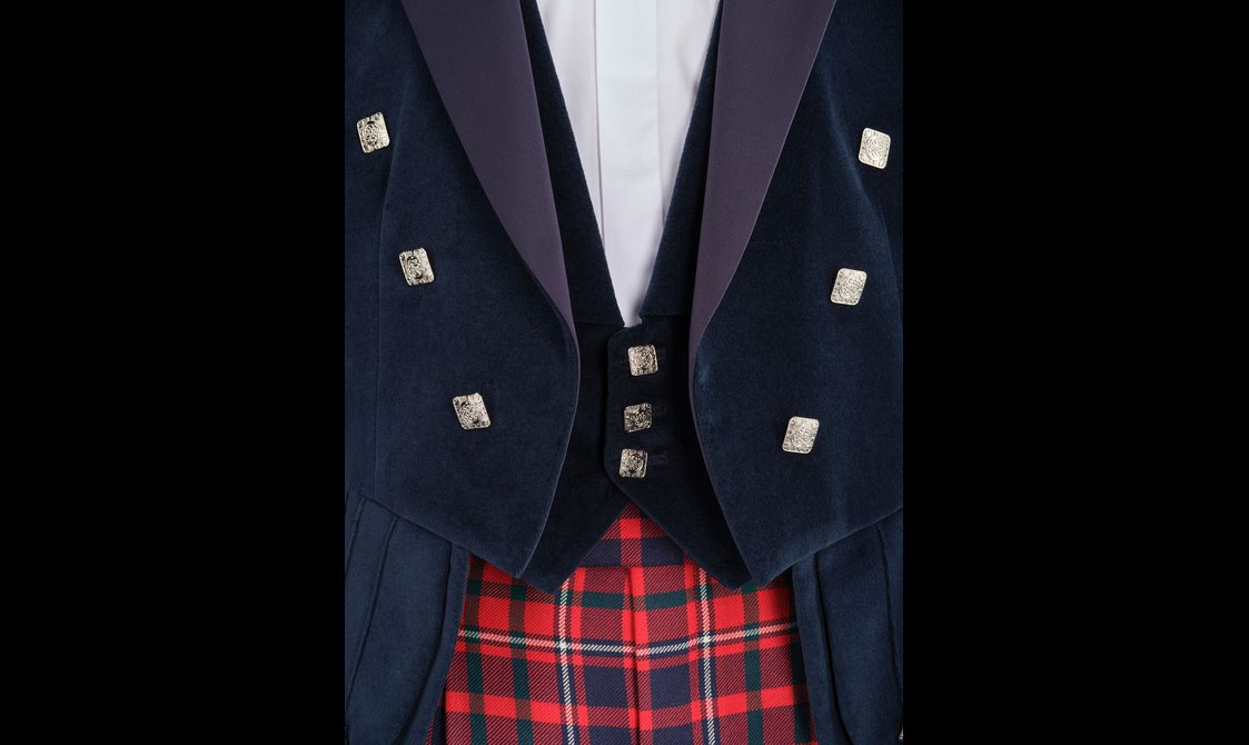 A close up of a navy velvet double waistcoat, white shirt, and red tartan trousers