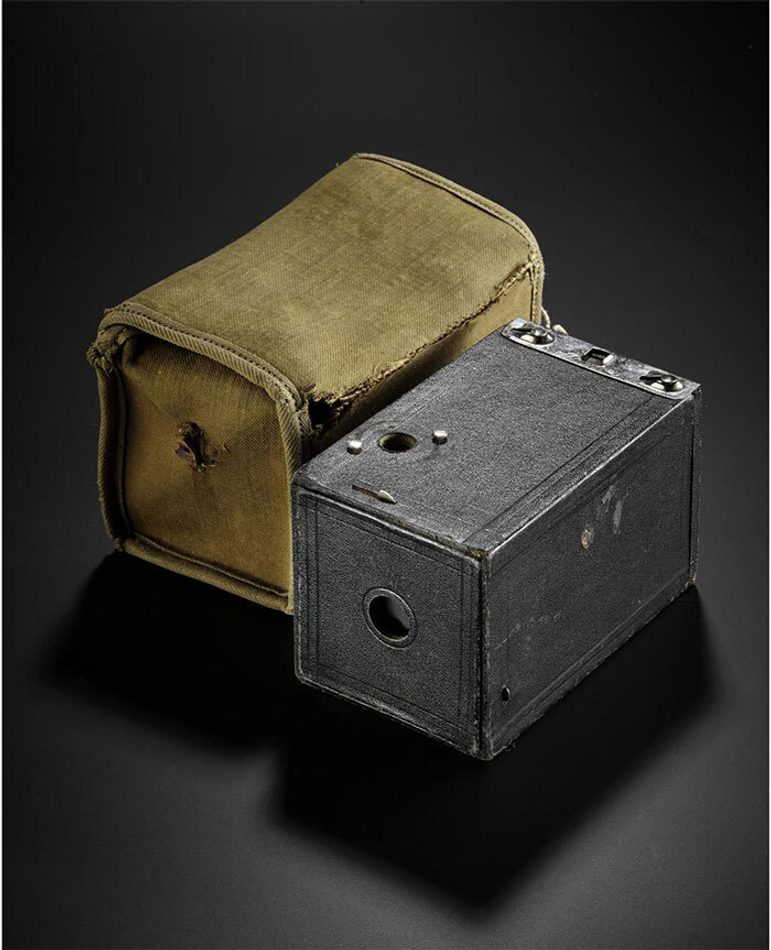 A grey steel rectangular box beside a canvas case against a black background