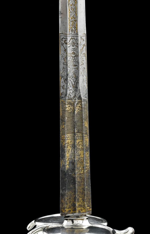 A detail of a long silver sword with inscriptions on the surface.