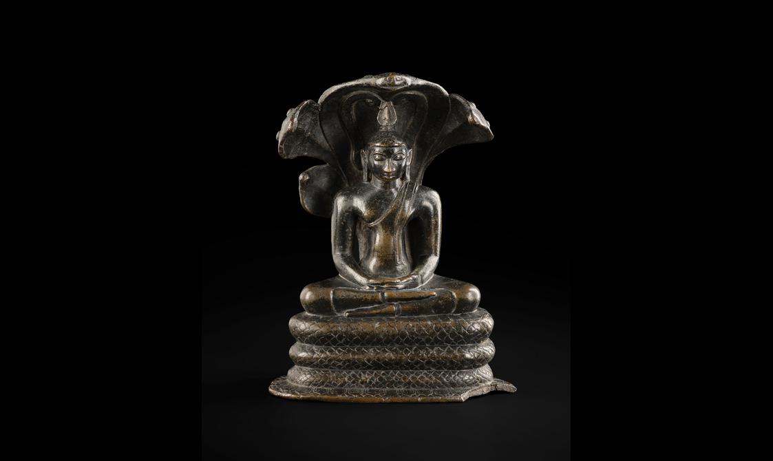 A bronze sculpture of a Buddha figure sitting cross-legged with a carved hood on its back.