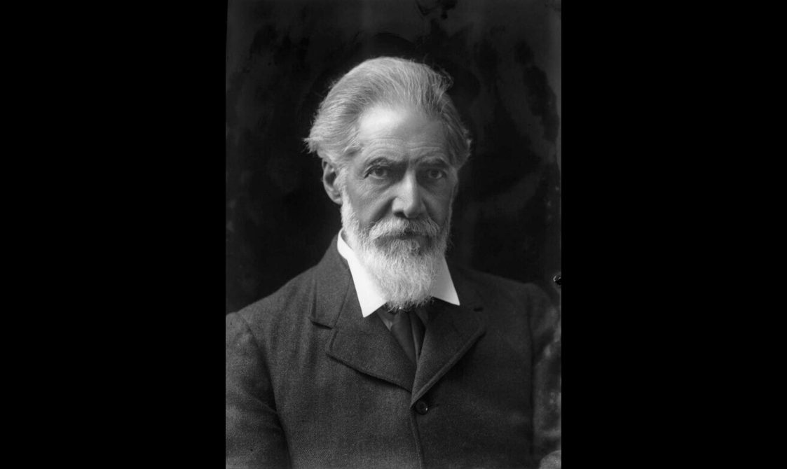 Black and white headshot of a man with white hair and a beard.
