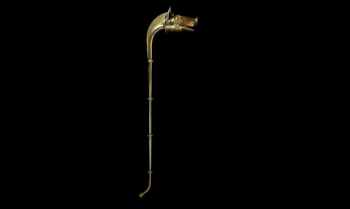 A brass carnyx with a long stem and head of a boar-like animal.