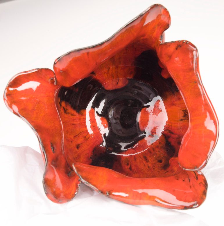 The inside of a red and black poppy made from glazed ceramic.