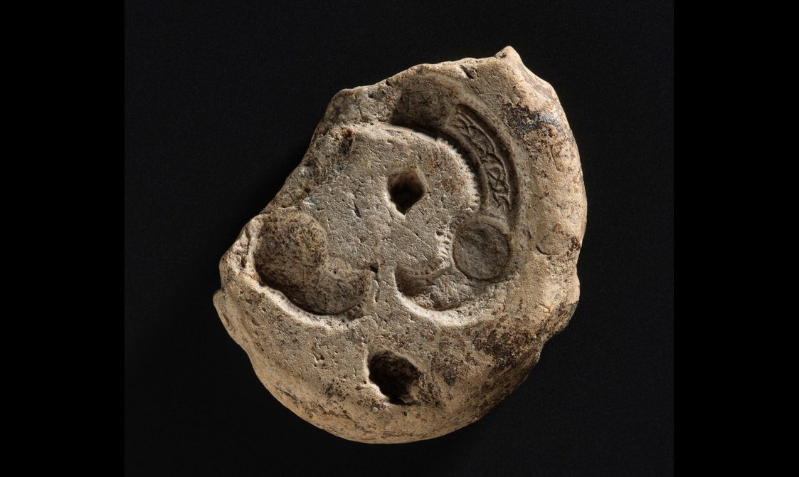 A piece of a yellowish rock with carving and indents on its surface