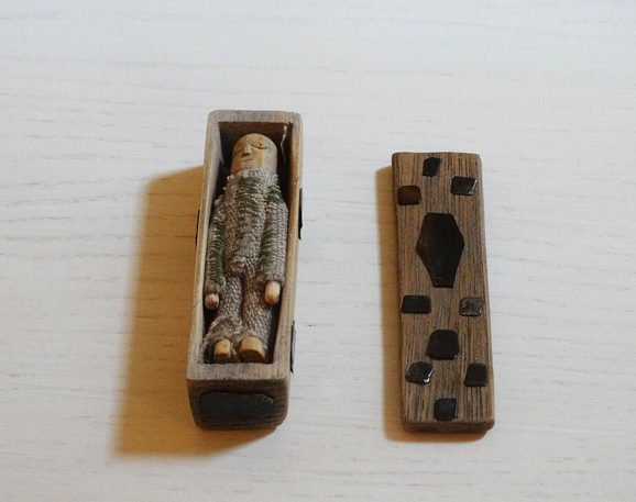 A small wooden figure of a corpe, in a small crafted wooden coffin. It's been made in the same style as the rest of the Arthur's Seat coffins.