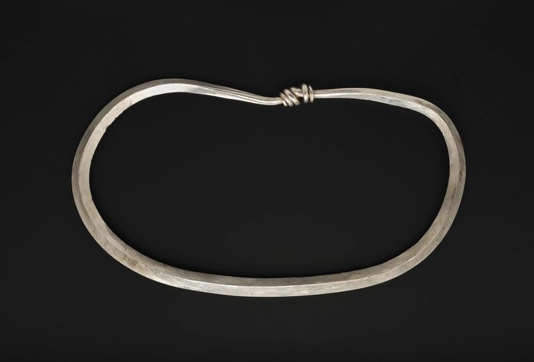 A plain thin band of silver bent into a bracelet shape.