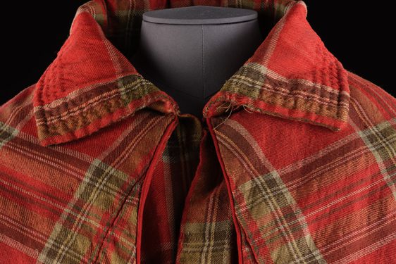 Detail of a red tartan cloak with a large colloar