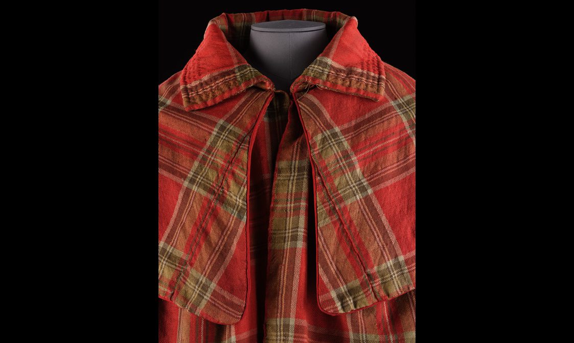 Detail of a red tartan cloak with a large colloar