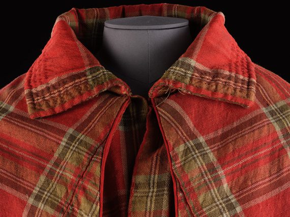 Detail of a red tartan cloak with a large colloar