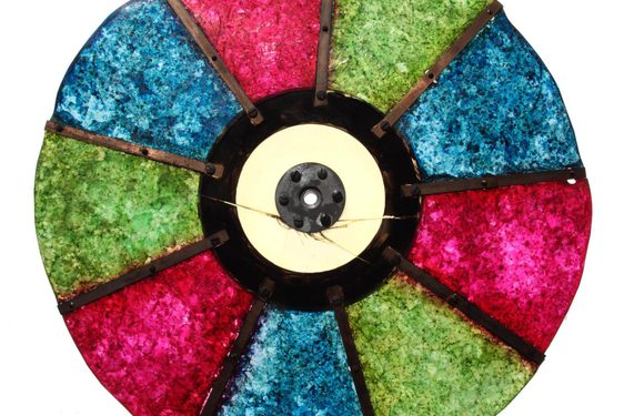 A colour photograph of a circular disc made up of red, blue and green semi-opaque panes against a white background. There are 2 of each colour alternating and connected by a central solid hub.